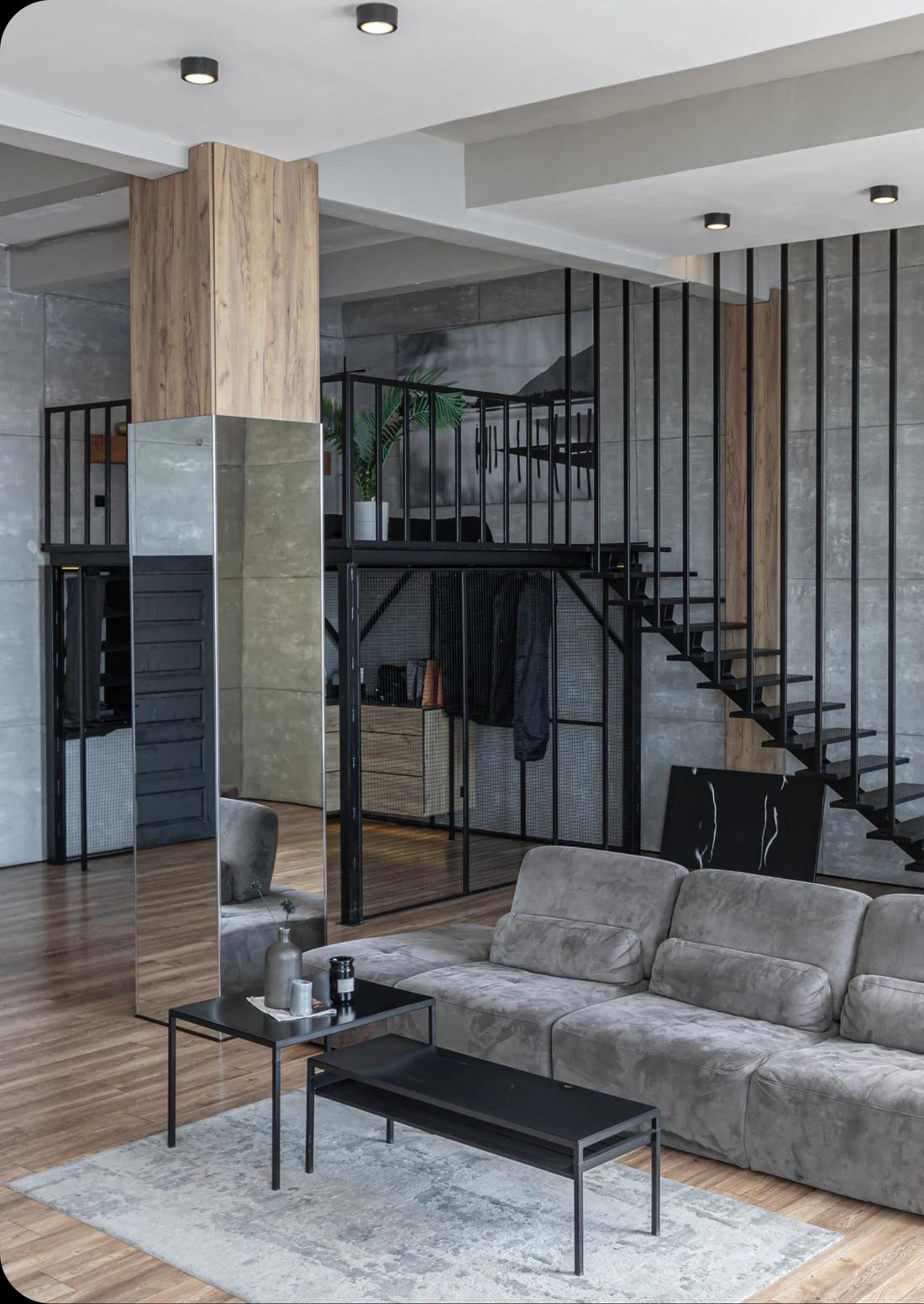 Loft interior with concrete surfaces, black steel framing, and a grey sofa